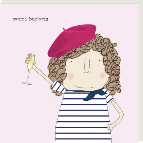 Merci Buckets Greeting Card from Rosie Made a Thing - a stylized illustration of a lady with curly brown hair wearing a pink beret and a navy-and-white striped shirt, holding a glass of champagne. The text 'merci buckets' appears in the upper left on a pale pink background.