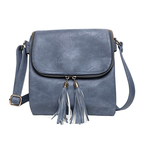 Long & Son denim blue faux-leather crossbody bag with a front flap, gold-tone hardware, and two matching tassel zip pulls.