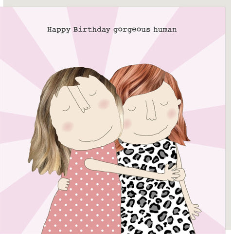 Gorgeous Human Greeting Card from Rosie Made a Thing - a square greeting card featuring a pink and lavender sunburst background with the text 'Happy Birthday gorgeous human' above an illustration of two girls hugging. The girl on the left wears a pink dress with white polka dots, and the girl on the right wears a black-and-white leopard print dress.